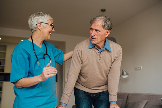 Nurse helping senior man with her walking device as part of the healthcare services offered through Fellowship Square senior living. 